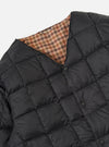 Close-up of the TAION x Universal Works Reversible Black Military Line Liner Jacket on a white background. Shows the black quilted material and the brown houndstooth pattern on the reverse side.