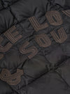 Close-up of the TAION x Universal Works Reversible Black Military Line Liner Jacket. Features black quilted fabric with embroidered brown lettering. 