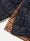 Close-up of the TAION x Universal Works Reversible Dark Navy Military Line Liner Jacket on a white surface. Shows the dark navy quilted material and the brown houndstooth reversible side.