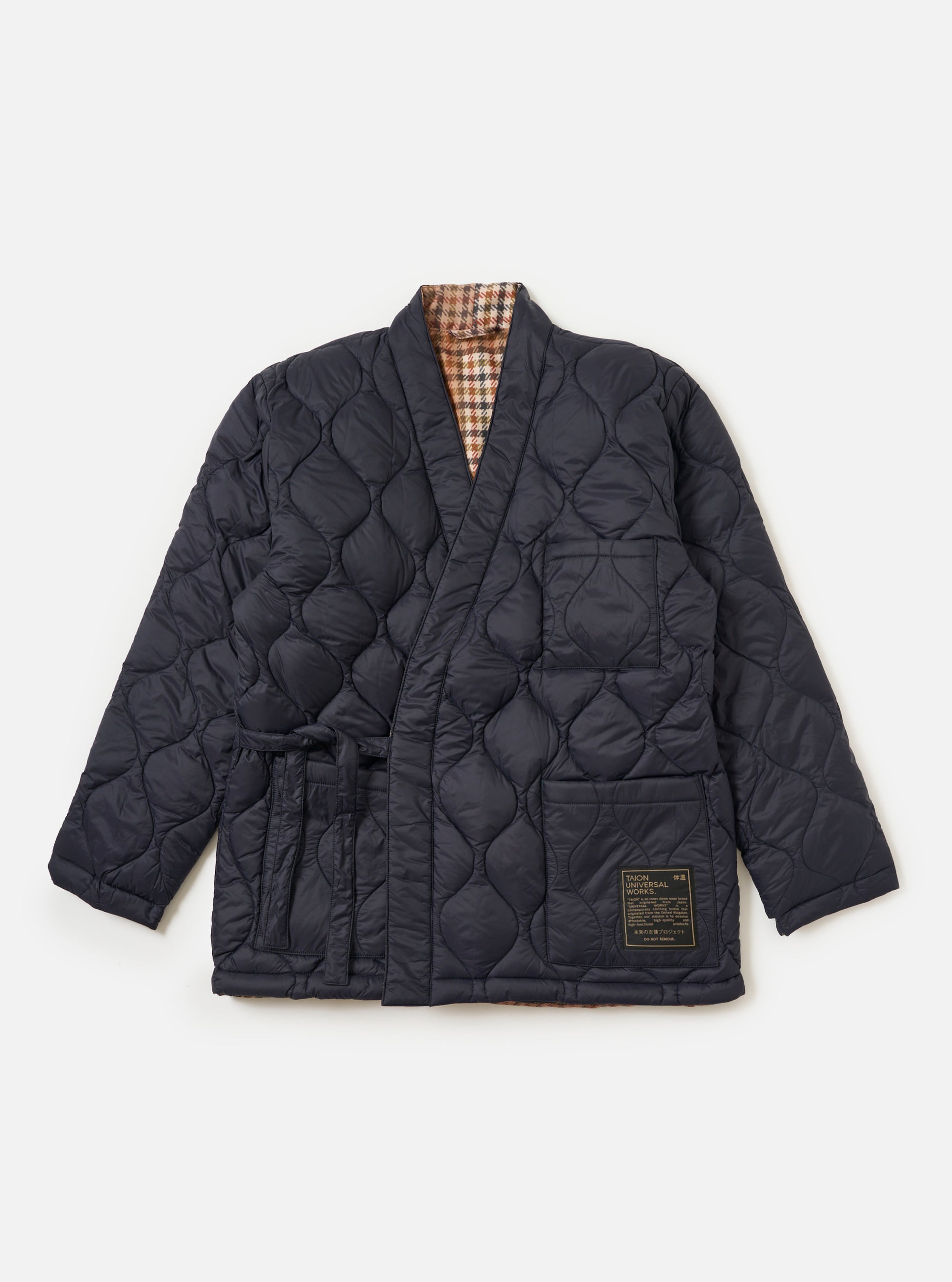 The TAION x Universal Works Reversible Dark Navy Military Line Kyoto Work Jacket is laid on a white background, showcasing its quilted texture and reversible houndstooth lining.