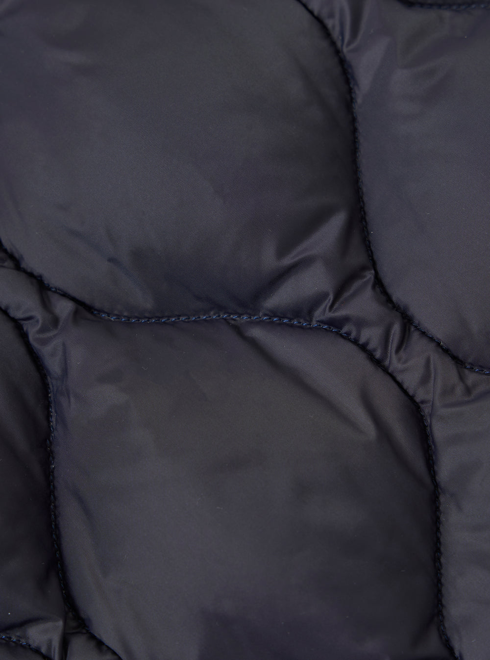 Close-up of the TAION x Universal Works Reversible Dark Navy Military Line Parka showing the quilted texture and dark navy color of the material.