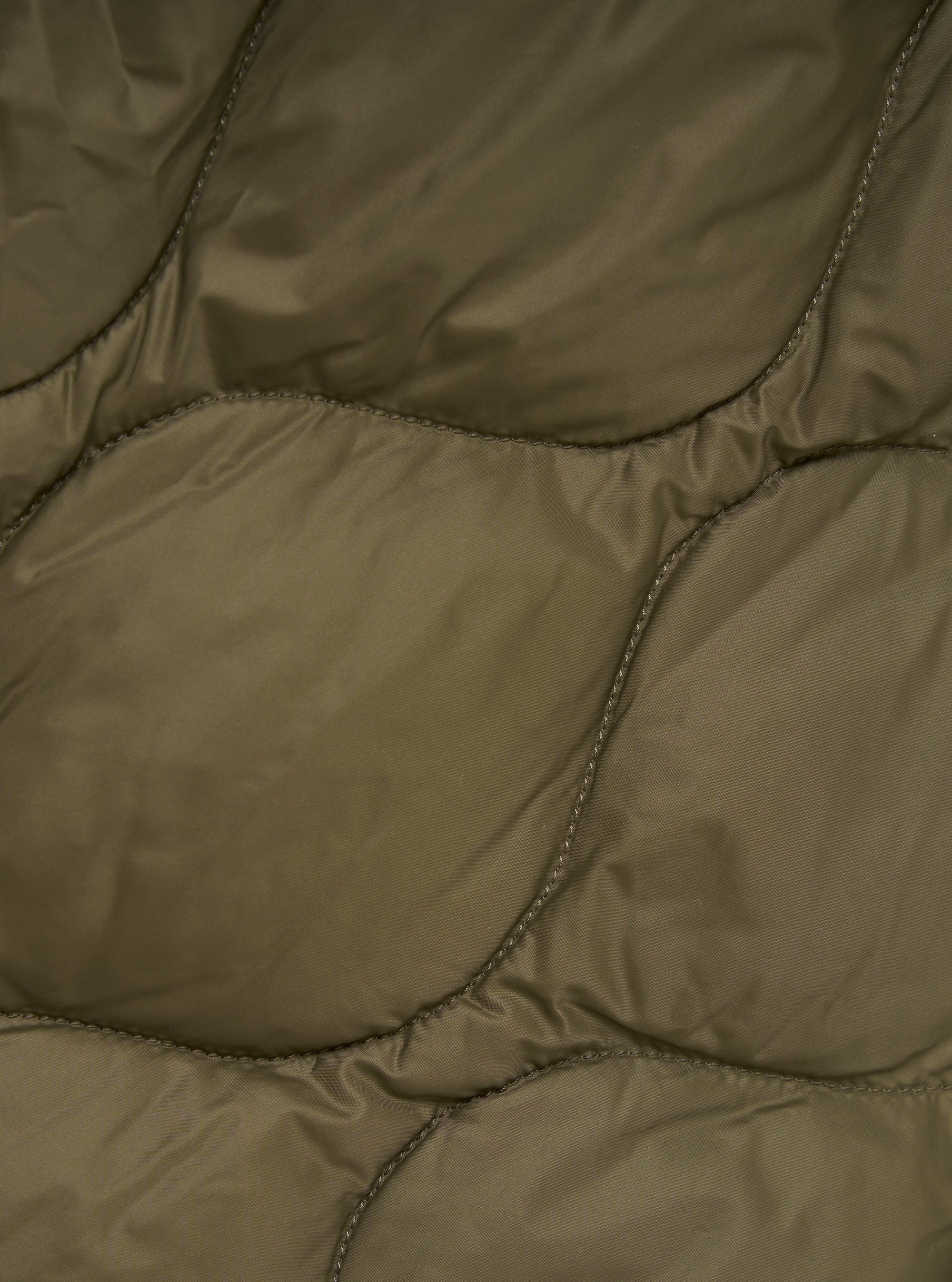 Close-up of the TAION x Universal Works Reversible Dark Olive Military Line Parka, showcasing its quilted texture and dark olive color. The material appears smooth and durable.