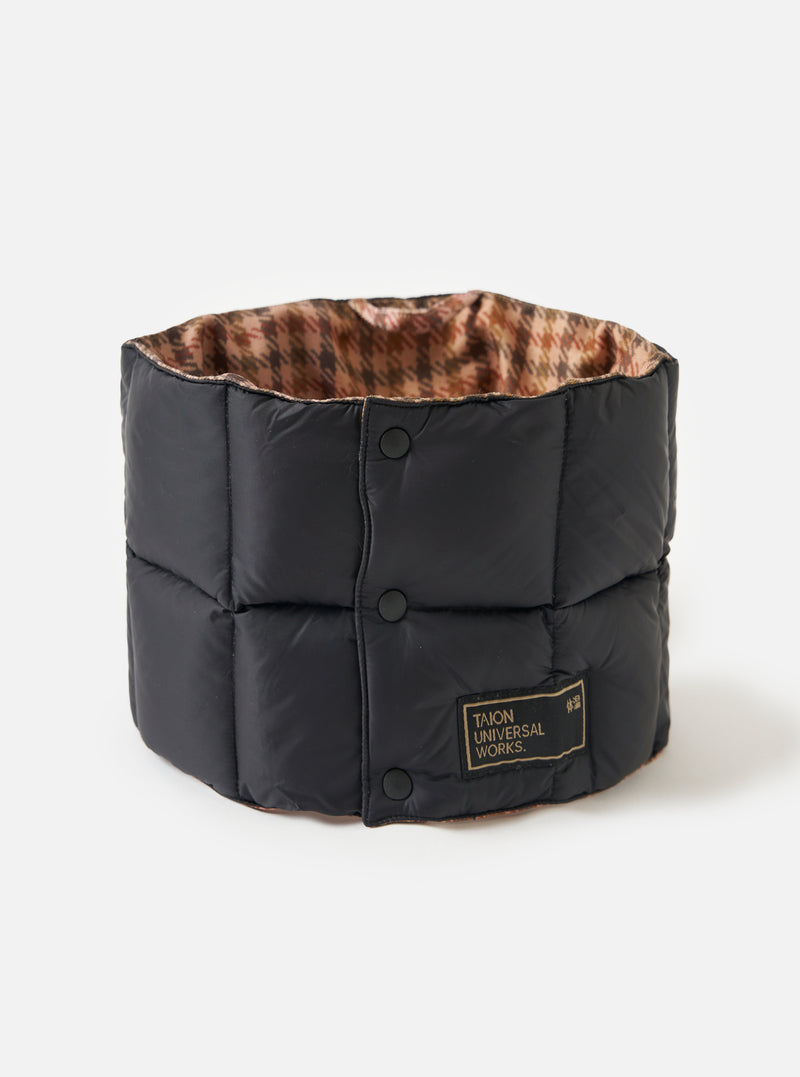 The TAION x Universal Works Reversible Black Military Line Neck Warmer on a white background. It's black with a houndstooth pattern on the inside and has a branded tag.