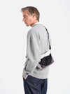 A model showcases the F/CE.® White Nylon Cordura Sil Sacoche. The bag features white, black, and gray nylon. Shot in a studio with a white background.