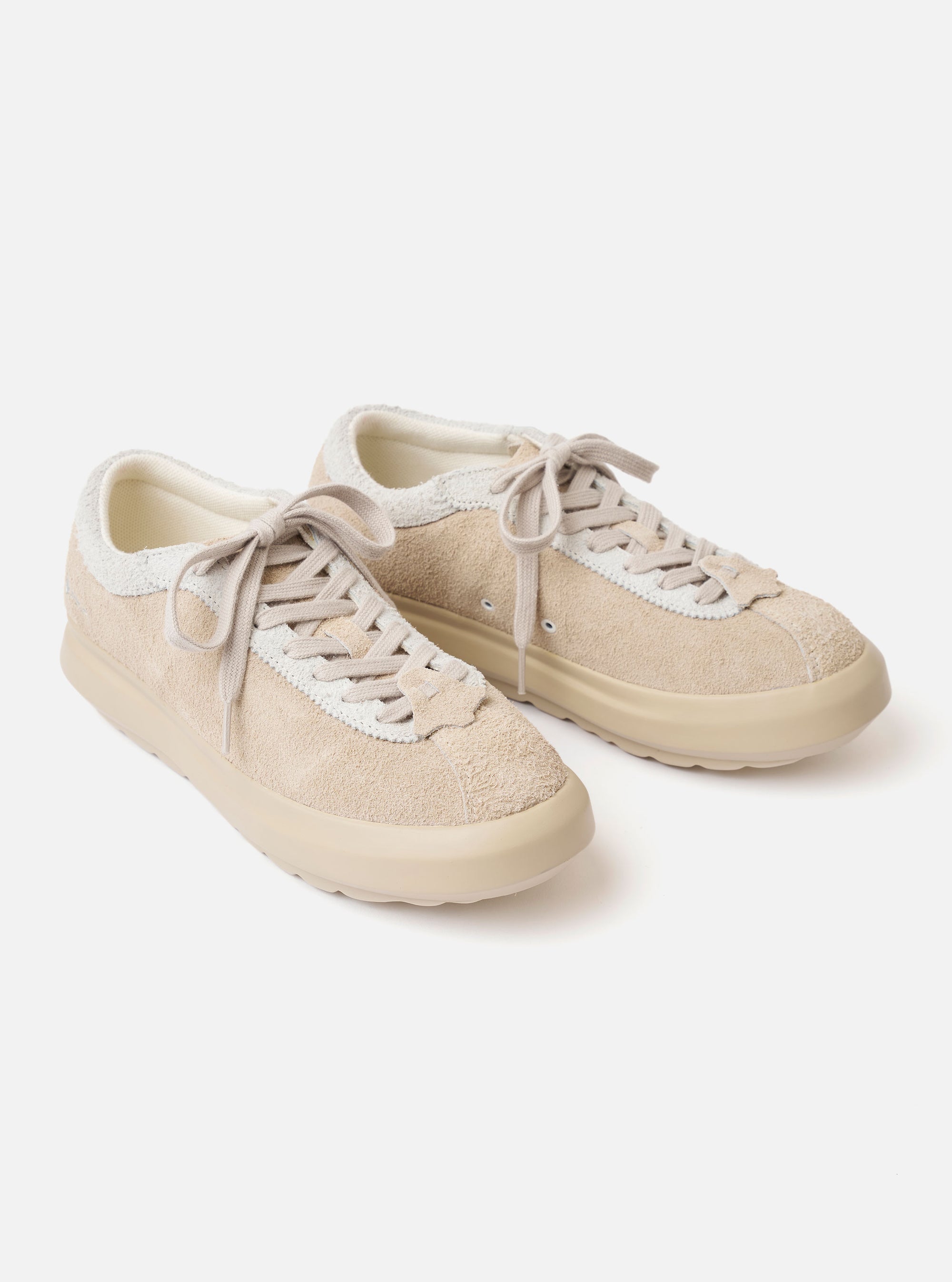 The Wander etc. 'The 70's' in Bone Hairy Suede/Leather is shown from a rear three-quarter angle as a flat lay against a plain white background. The image highlights the shoe's bone-colored hairy suede upper, tonal stitching, and a signature chunky off-white sole. A small black brand tab is visible on the side.