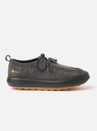 The Wander etc. FD/08 Low in Black Asphalt/Gum Hairy Suede is shown in a studio shot against a plain white background. The shoe features a black hairy suede upper with a low-cut silhouette, slim black laces, and a prominent chunky gum rubber sole. The textured finish of the suede and the contrast between the black upper and the tan-colored sole are clearly visible.