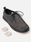 The Wander etc. FD/08 Low in Black Asphalt/Gum Hairy Suede is shown from a side profile as a flat lay against a plain white background. The shoe features a black hairy suede upper, slim black laces, and a chunky gum rubber outsole. The low-cut design and textured leather are the prominent features.