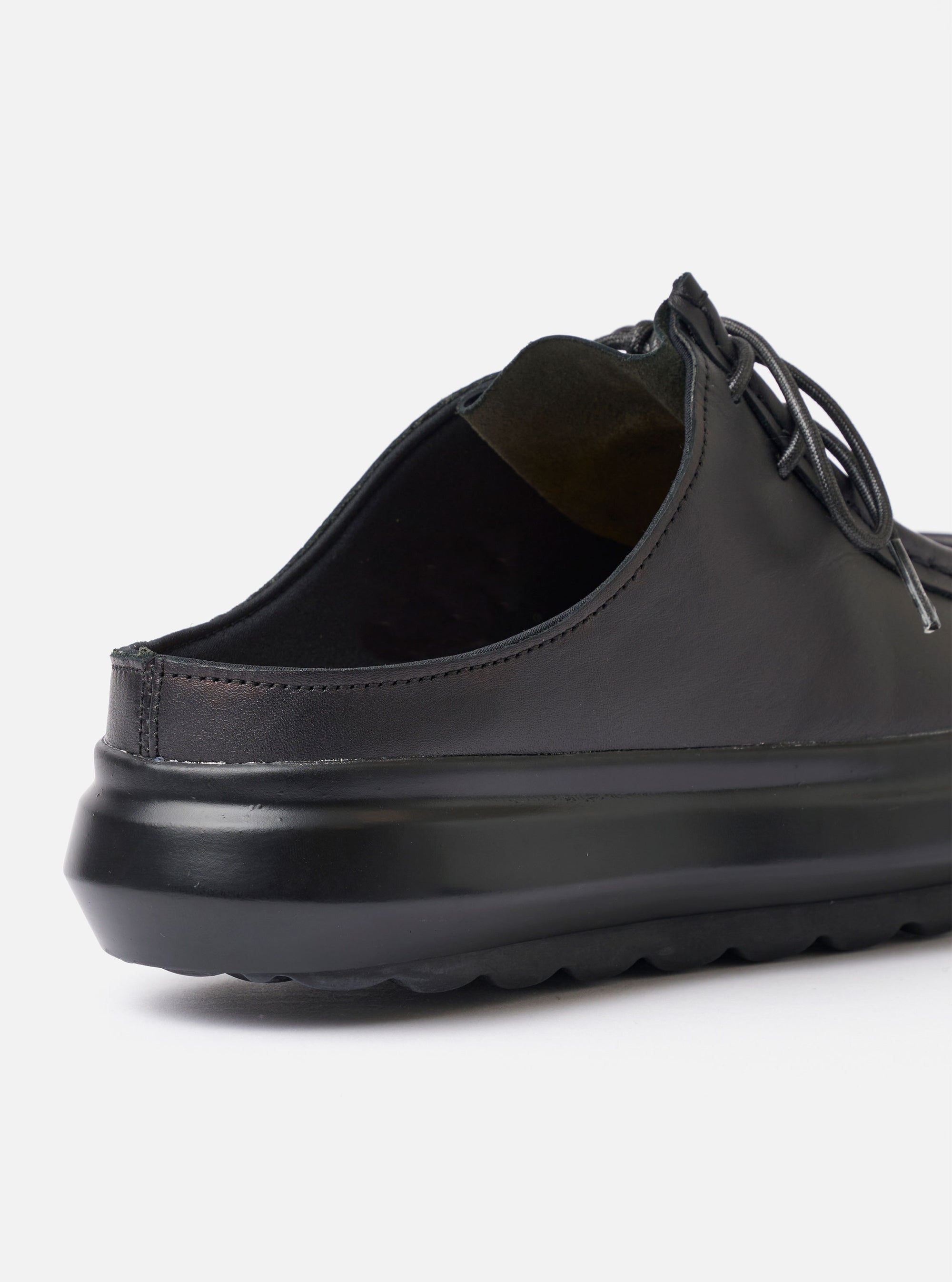 The Wander etc. Laze in Black Nappa Leather is shown as a flat lay against a plain white background. The footwear features a backless mule silhouette with a smooth black nappa leather upper and a signature chunky black outsole. The image highlights the clean slip-on design and the substantial profile of the sole.