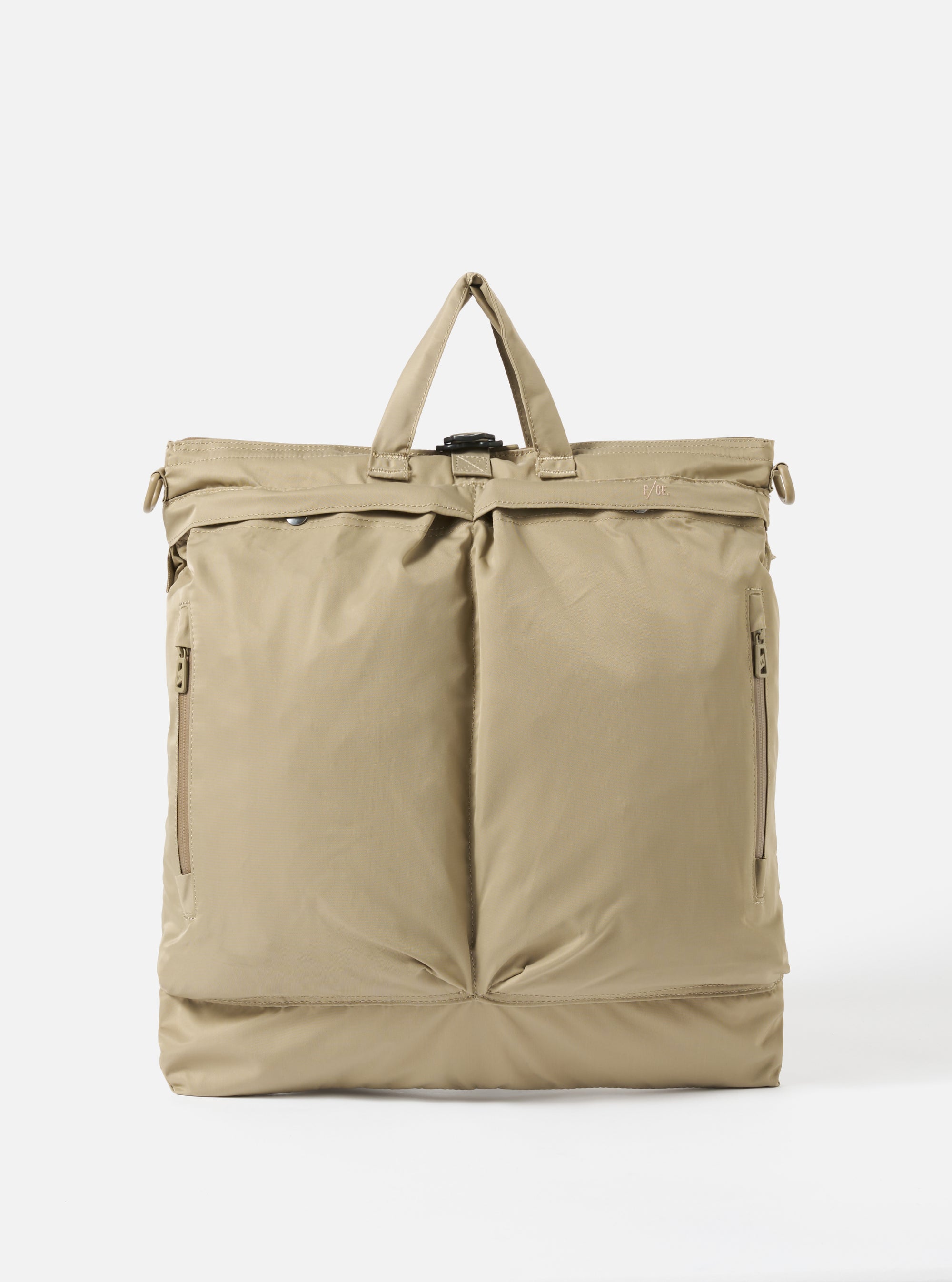 The F/CE.® Sage Green Recycled Twill 3-Way Helmet Bag is displayed on a white background. The bag is sage green and made of recycled twill. It has a top handle and two front pockets.