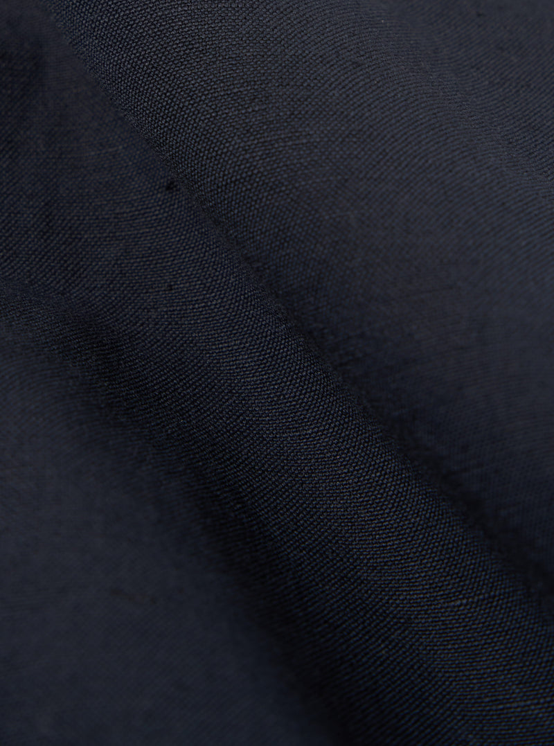 Close-up of the navy linen slub weave simple short fabric. The texture is visible, showing the weave pattern. The fabric is draped, creating shadows and highlights.