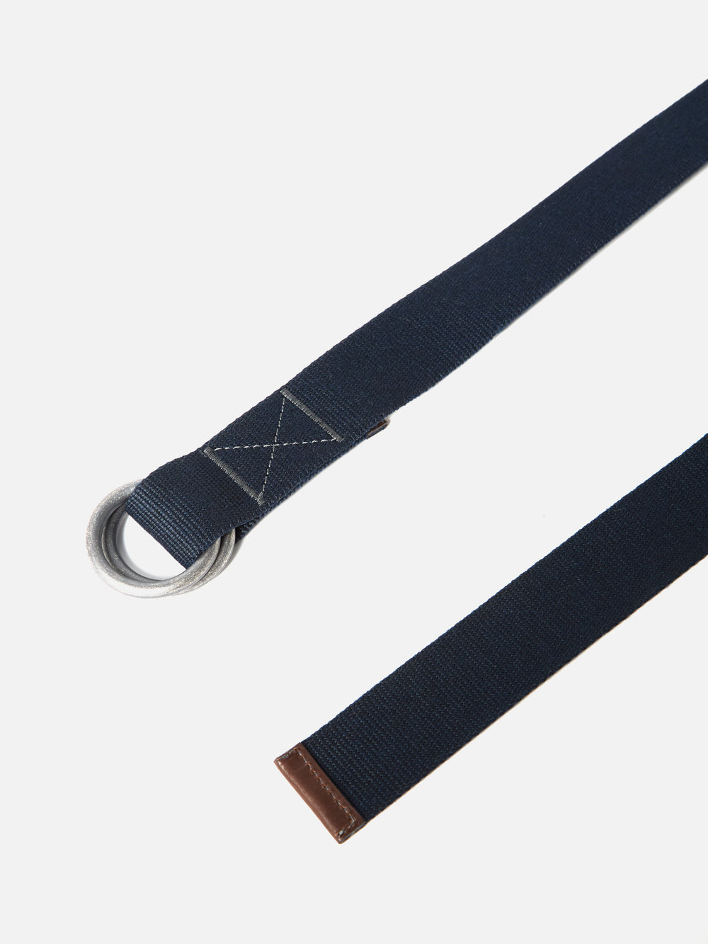 Close-up of a Navy Canvas O Ring Belt on a white background. The belt is made of navy canvas with a silver O-ring buckle and brown leather tip.
