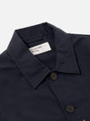 Close-up of the Navy Linen Slub Weave Bakers Jacket. The jacket is navy with brown buttons and a visible brand label. Shot on a plain white background.