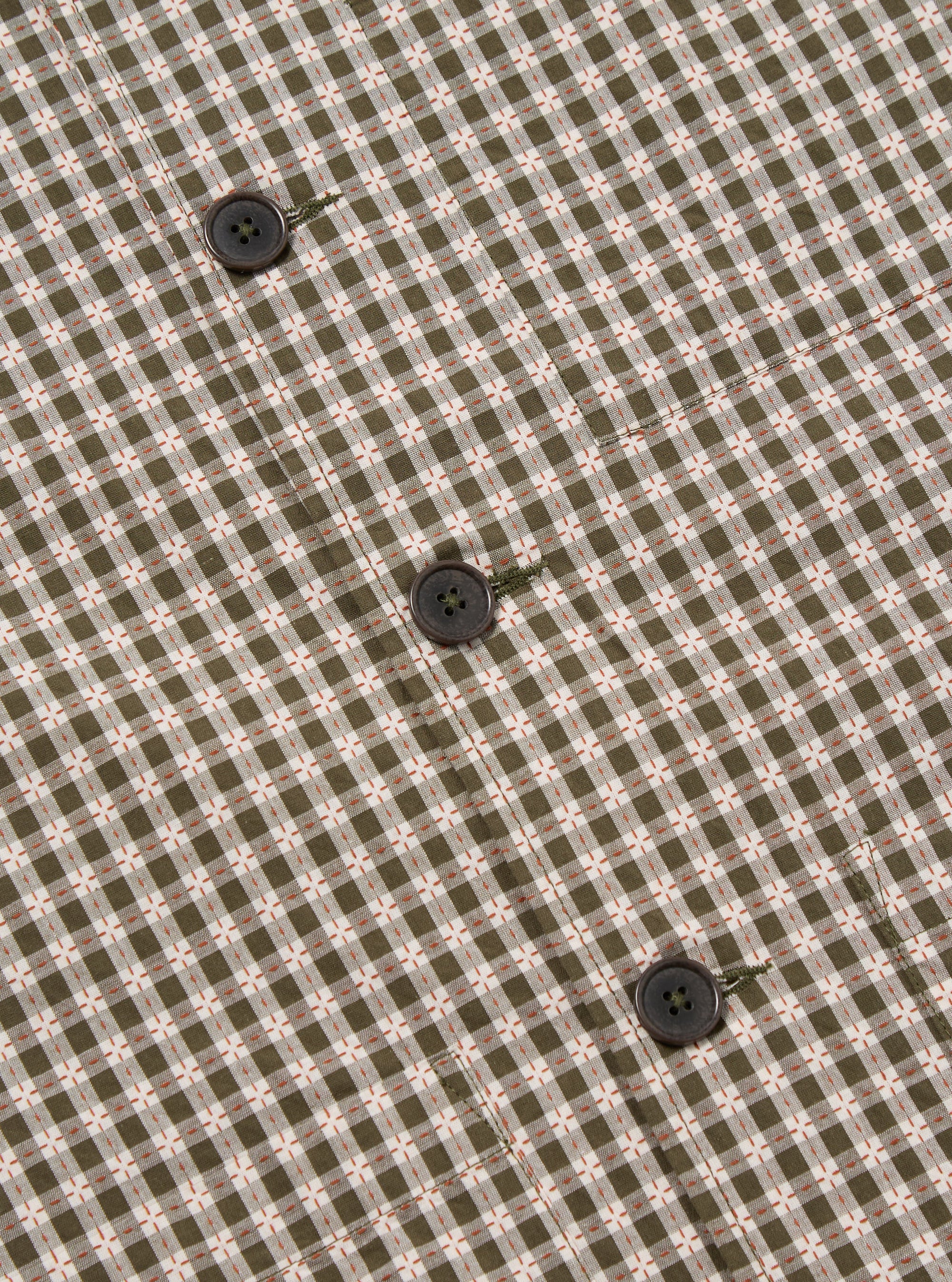 Close-up of the Olive Dobby Check Cancun Jacket fabric, showcasing the olive and white check pattern with small orange accents and dark brown buttons.