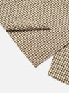 Close-up of the Olive Dobby Check Cancun Jacket fabric. The jacket has a green and white check pattern with red accents, laid on a white surface.