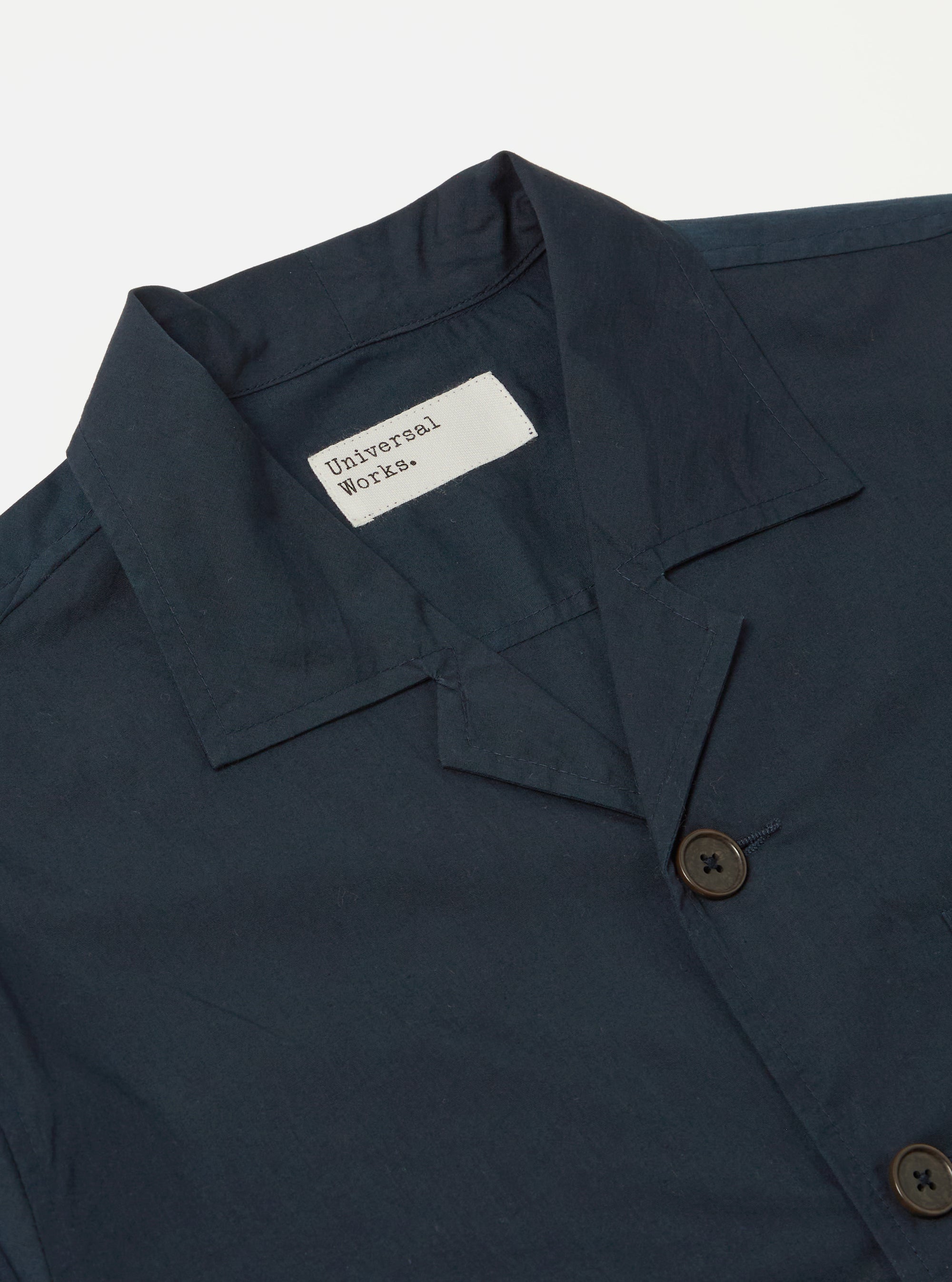Close up of the Navy Broadcloth Cancun Jacket on a white background. The jacket is navy with brown buttons and a visible brand label.