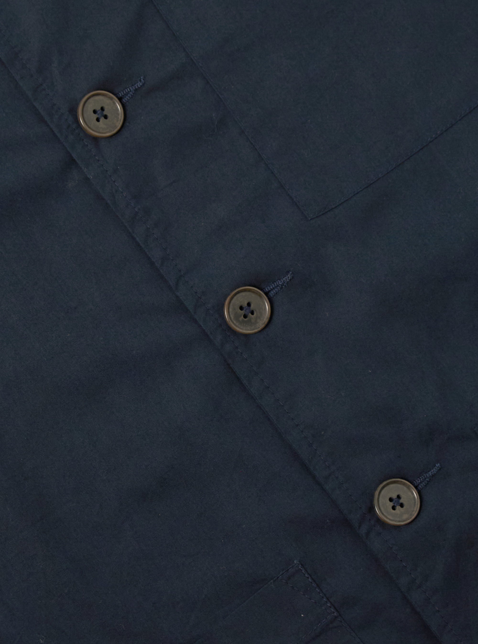 Close up of the navy Broadcloth Cancun Jacket. The jacket is made of broadcloth and has a relaxed fit. The background is a plain white surface.