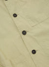 Close-up of the pale green Broadcloth Cancun Jacket. The jacket is made of broadcloth material and features brown buttons. The background is a plain white surface.