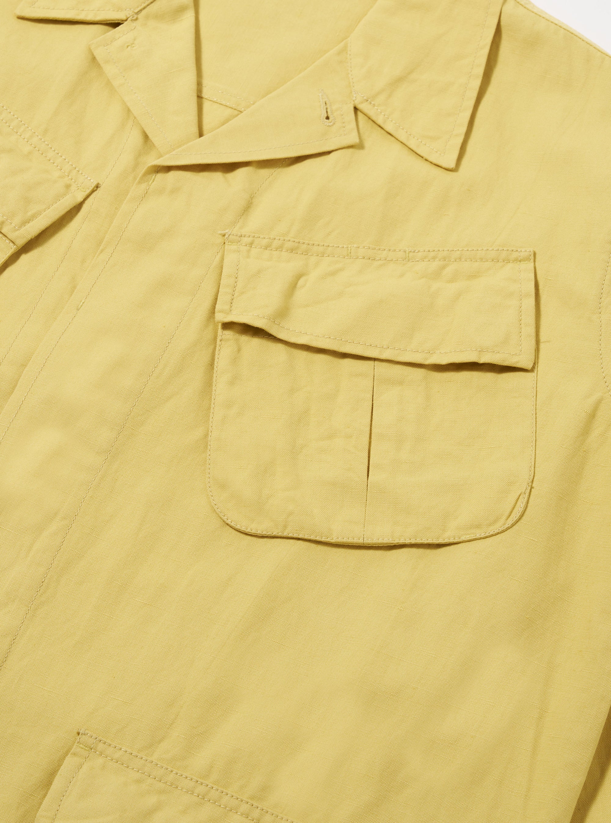Close-up of the Lemon Linen Slub Weave Jungle Jacket on a white background. The lemon-colored linen jacket features chest pockets and a relaxed fit.