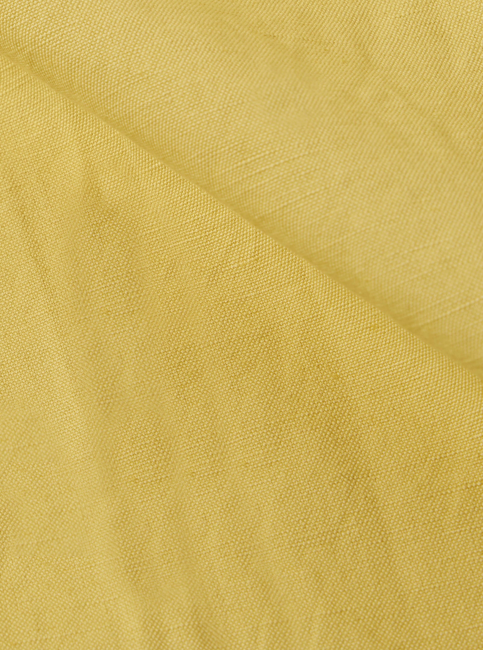 Close-up of the lemon-colored linen slub weave of the Jungle Jacket. The fabric's texture is visible, showcasing its natural fibers and subtle variations in color.