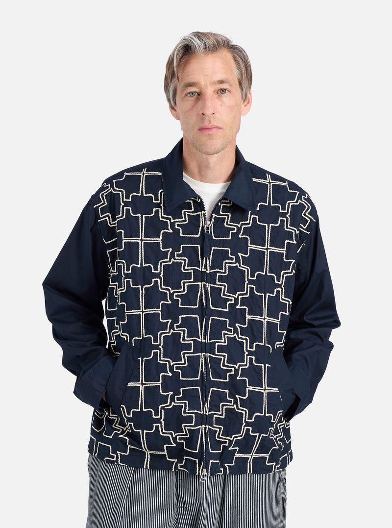 A model wears the Navy Mitla Broadcloth Club Jacket against a white backdrop. The jacket is navy with a white geometric pattern. It has a relaxed fit.