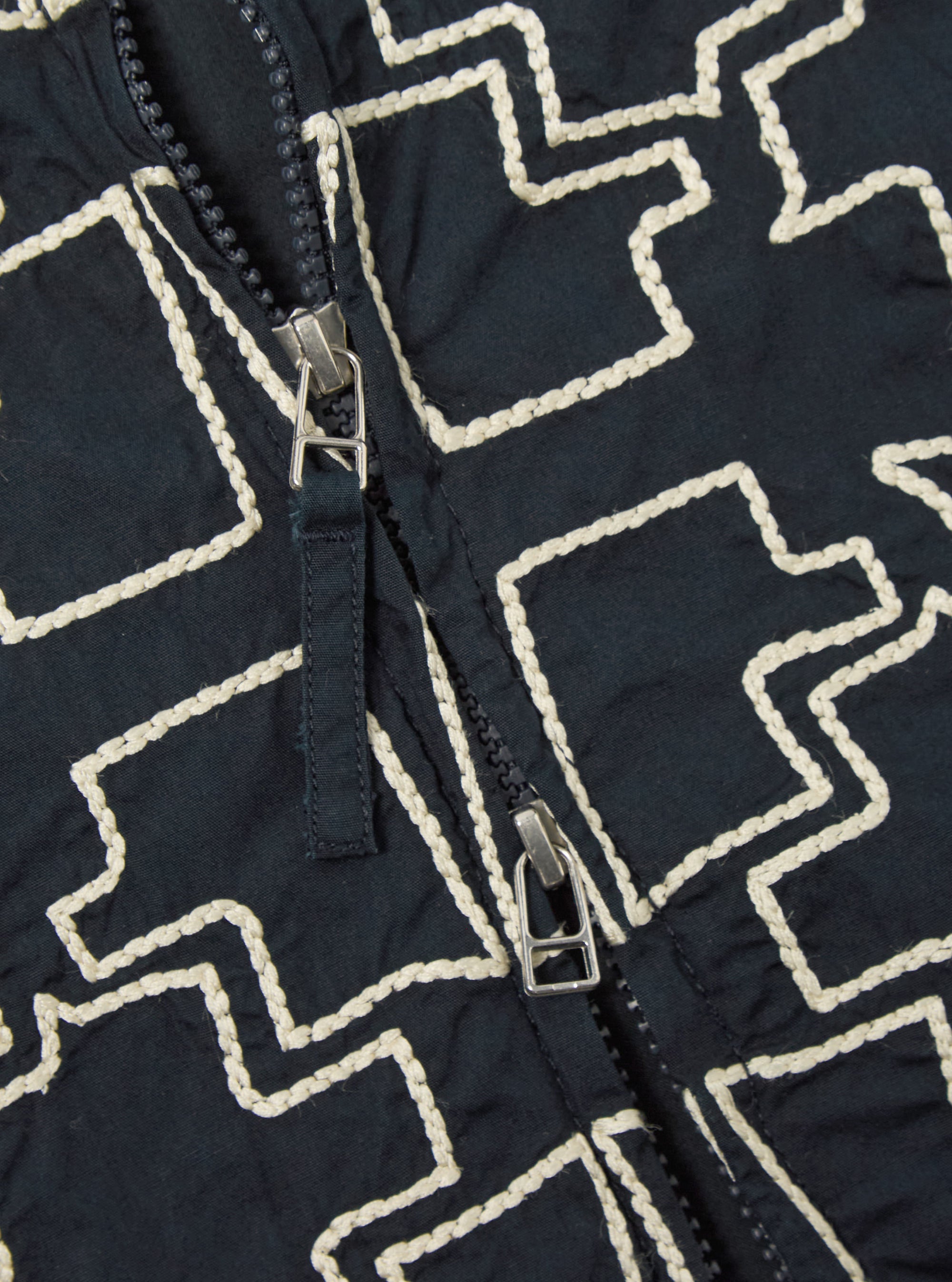 Close-up of the Navy Mitla Broadcloth Club Jacket. The jacket is navy with a white geometric pattern and a silver zipper. The background is a plain surface.