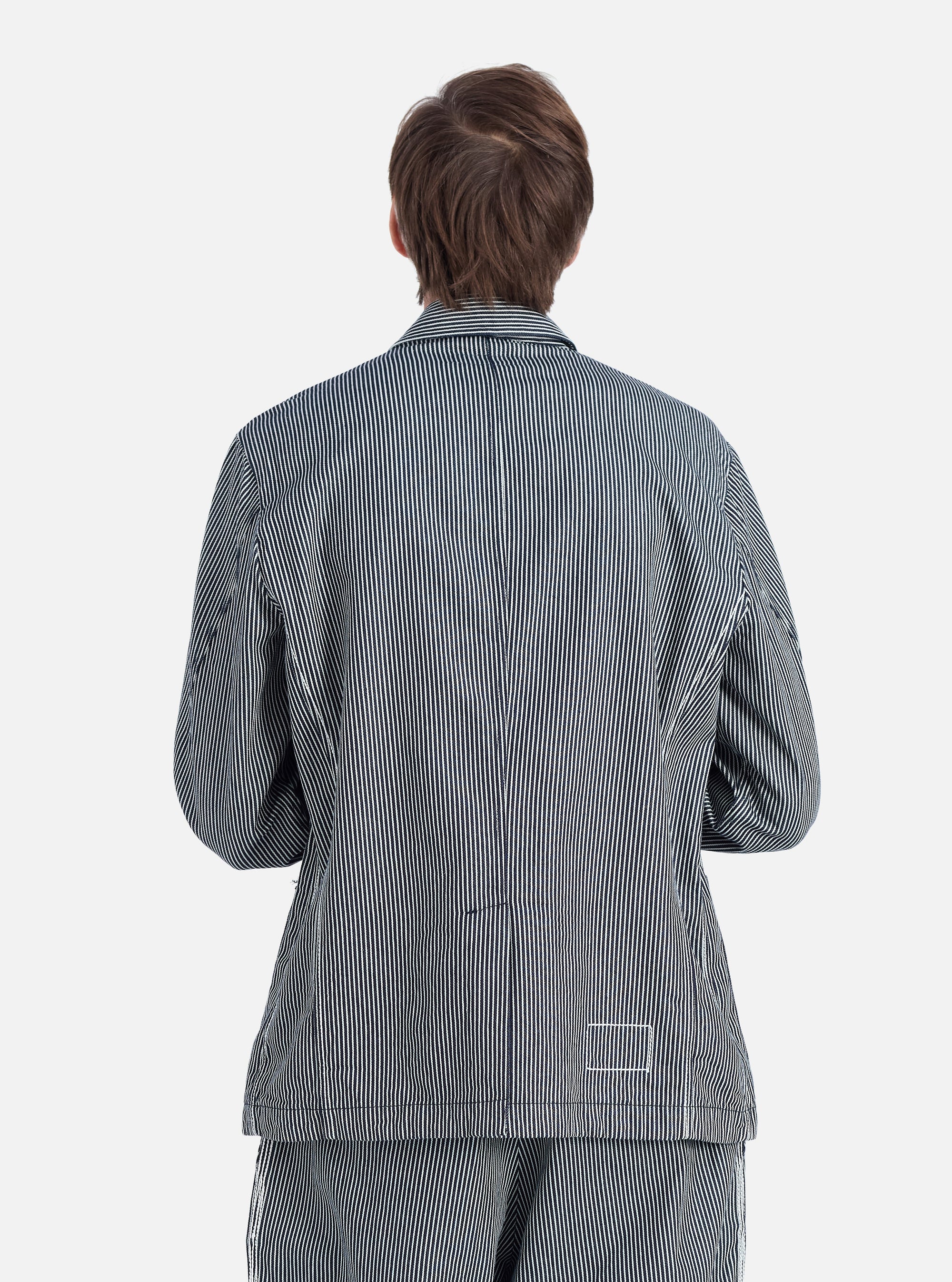Back view of a model wearing an Indigo Hickory Stripe Denim Original Bakers Jacket. The jacket is blue and white striped. Shot on a white background.