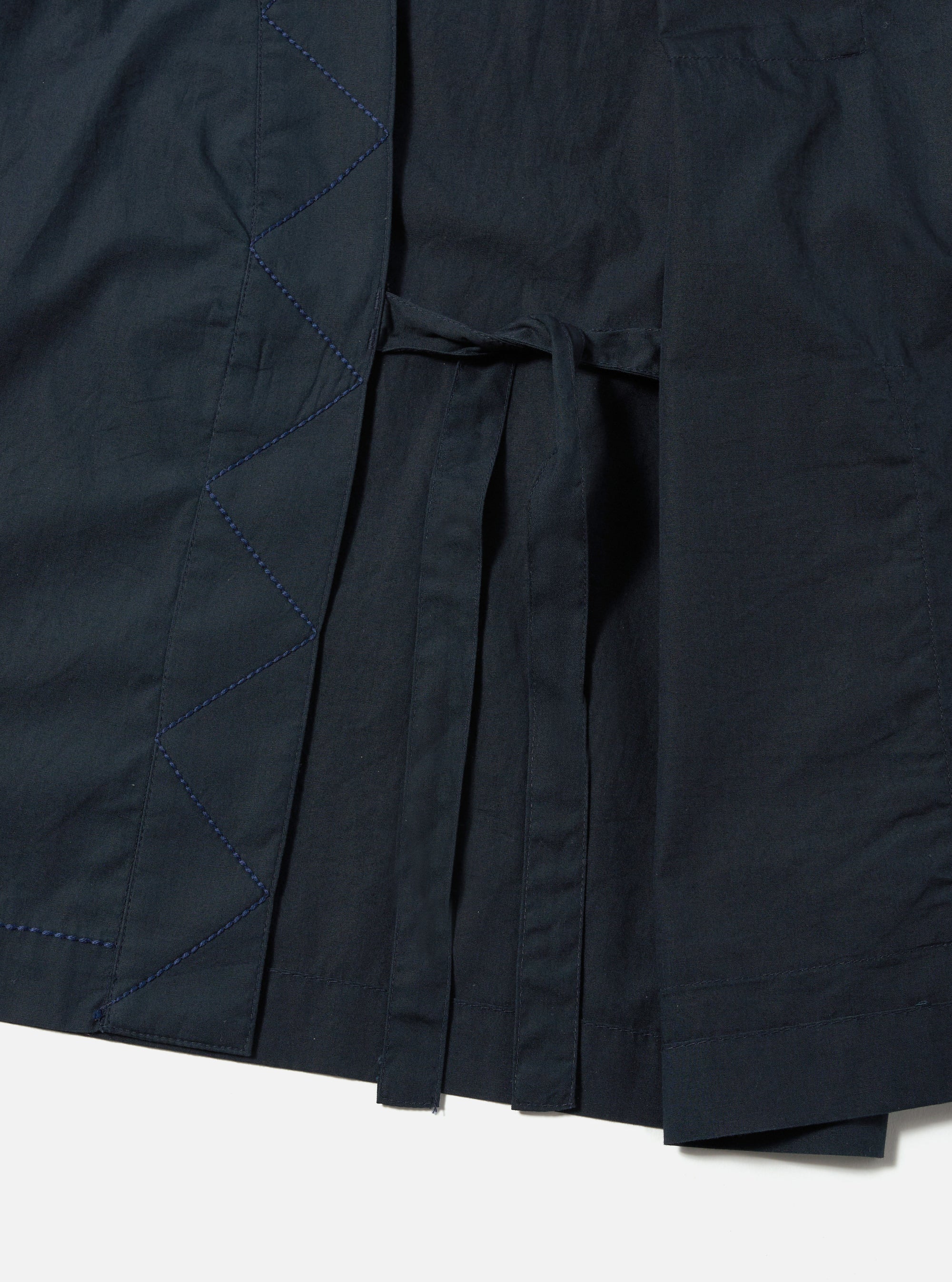 Close-up of the navy broadcloth Osaka Work Jacket, featuring a tie closure and detailed stitching. The jacket is displayed on a white surface.
