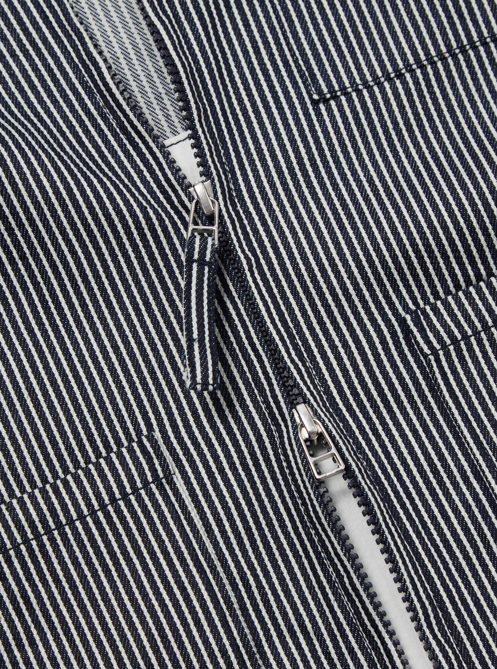 Close-up of the Indigo Hickory Stripe Denim Marine Gilet, showcasing the blue and white striped denim fabric and silver zipper. The image is shot on a flat, neutral surface.
