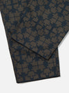 Close-up of the Navy Mitla Print Cotton Hi Water Trouser on a white surface. The cotton trousers feature a navy geometric print on a brown base.