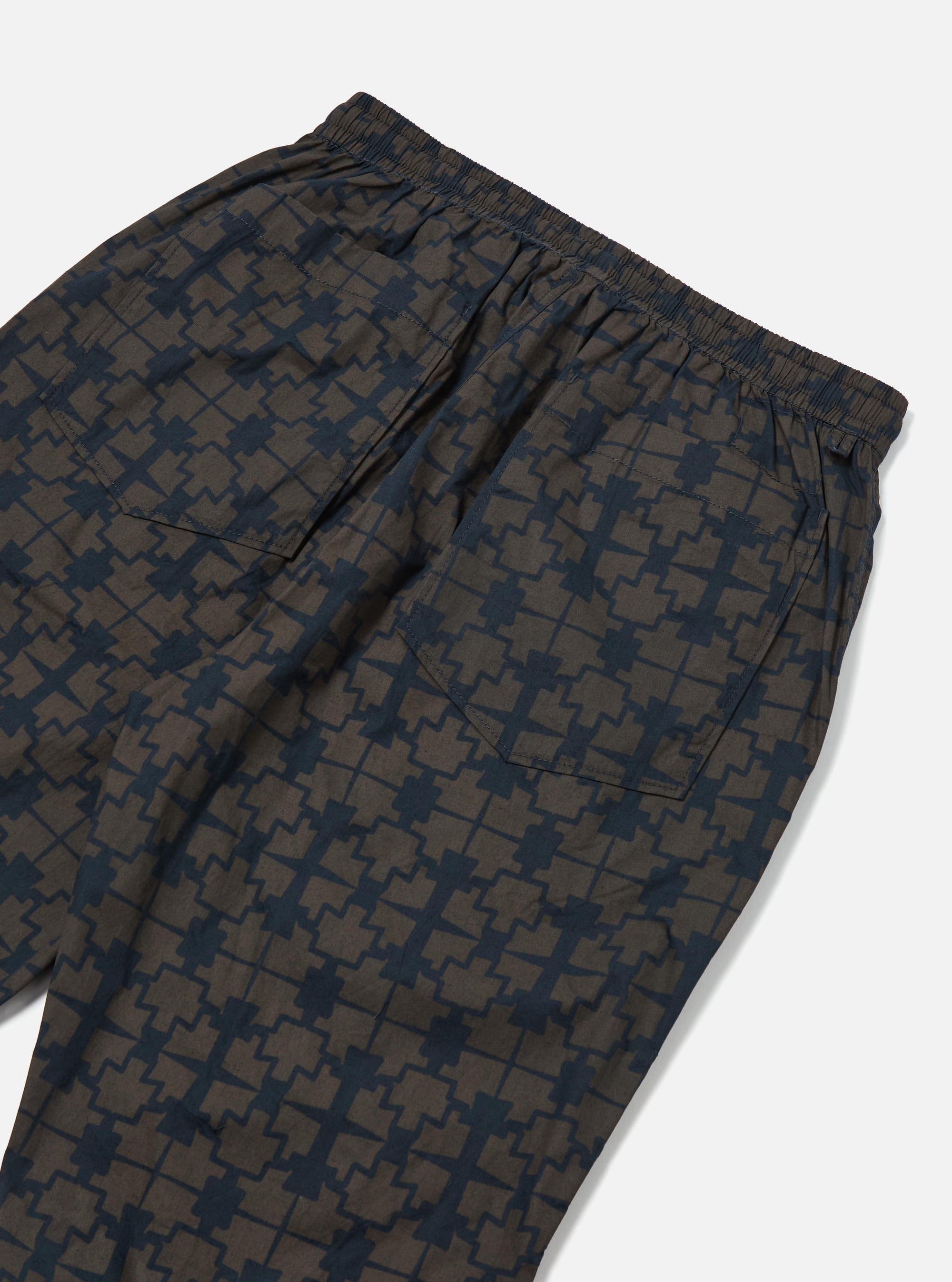 Close-up of the back of the Navy Mitla Print Cotton Hi Water Trouser on a white background. The cotton trousers have a navy and brown geometric print and an elasticated waist.