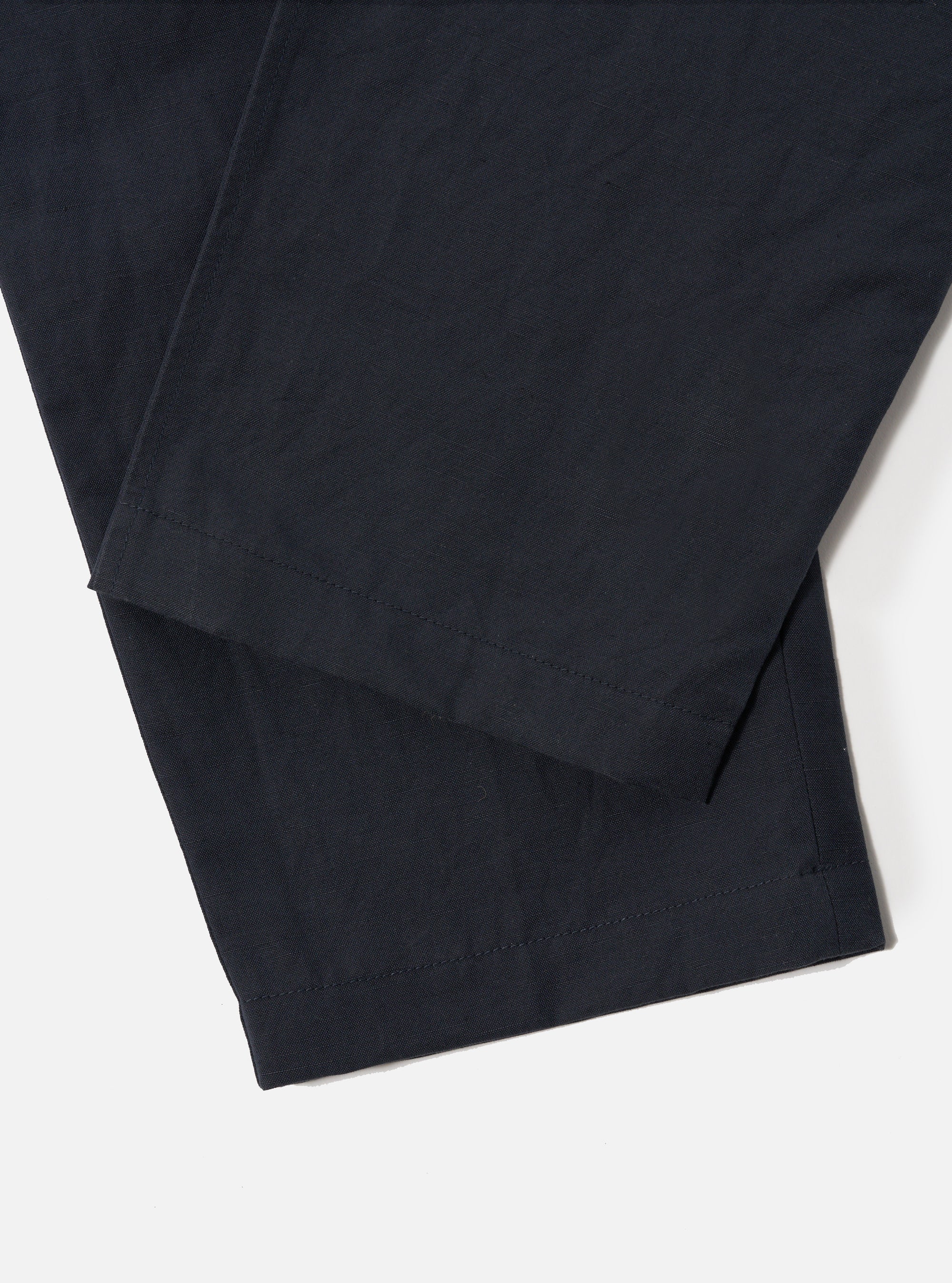 Close-up of the Navy Linen Slub Weave Oxford Pant on a white background, showcasing the fabric's texture and the pant's hem.