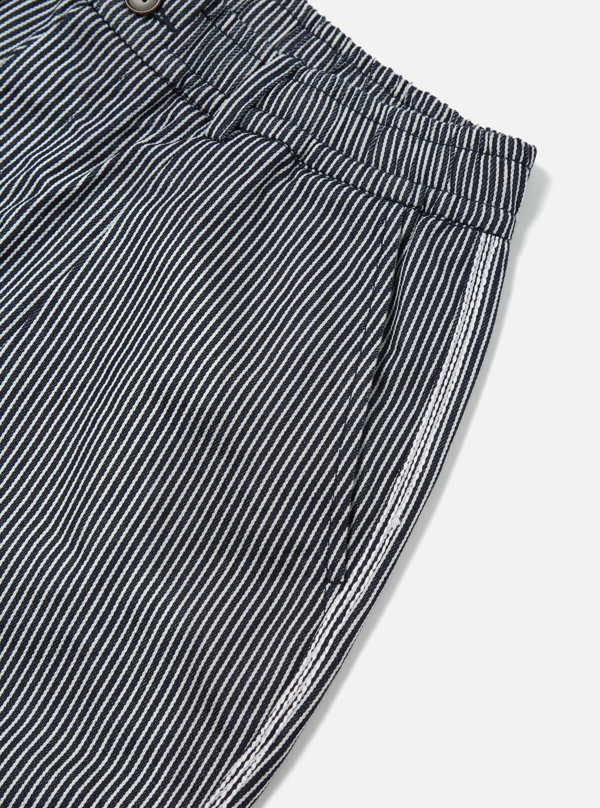 Close-up of Indigo Hickory Stripe Denim Pleated Track Short. Shows the striped denim material and pleated waist on a white background.