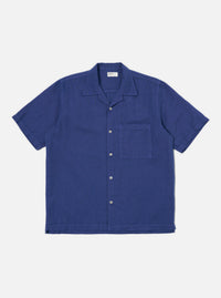 The Blue Linen Cotton Shirting Camp Shirt is laid flat on a white background. The shirt is a solid blue, short sleeved, and has a pocket on the right breast.