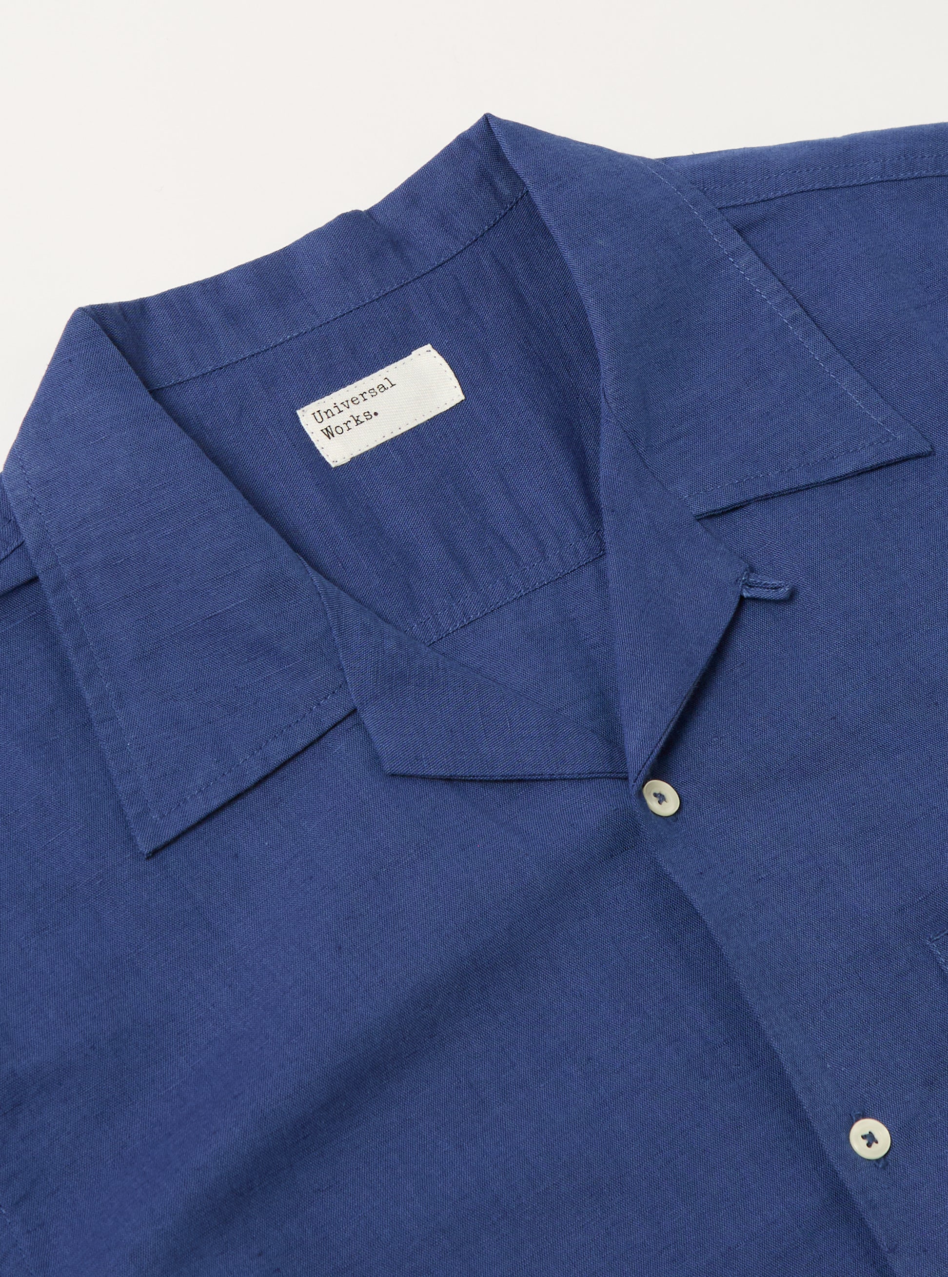 Close-up of the Blue Linen Cotton Shirting Camp Shirt. The blue linen-cotton blend is visible, along with the camp collar and button details. Shot on a white surface.