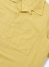 Close-up of the Lemon Linen Cotton Shirting Camp Shirt. The shirt is a light yellow color and has a pocket on the left chest. The background is a plain white.