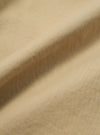 Close-up of the Sand Military Cotton Judo Pant fabric. The sand-colored cotton is draped to show texture. The background is a plain surface.