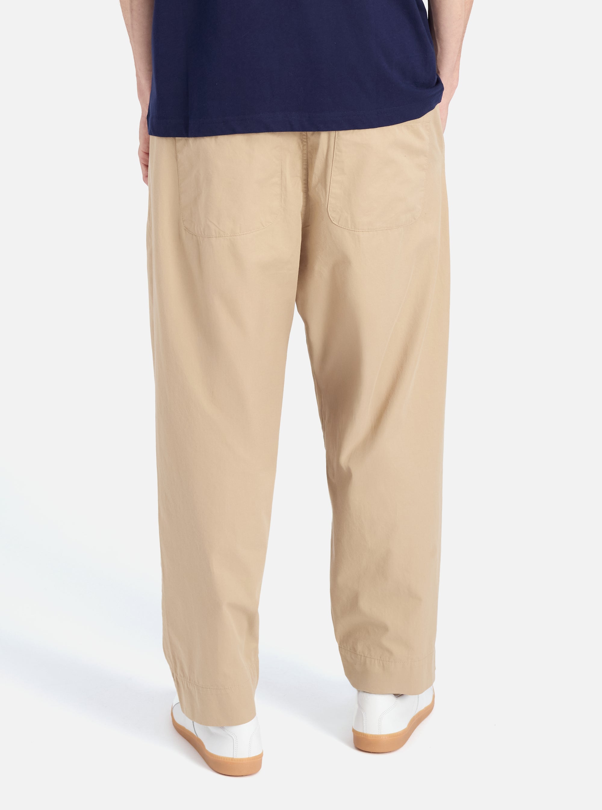 Back view of a model wearing the Sand Military Cotton Judo Pant. The pants are a light tan color and have a loose, comfortable fit. The background is a clean, white studio setting.