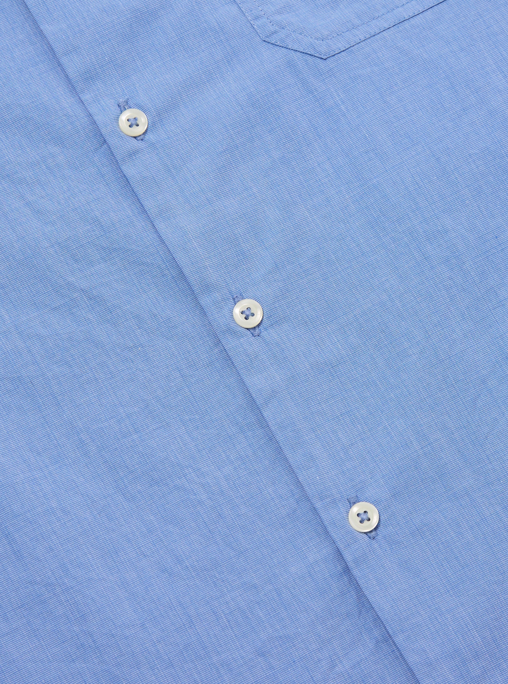 Close-up of the Blue End On End Cotton Garage Shirt. The light blue cotton fabric has white buttons. The shirt is on a flat surface.