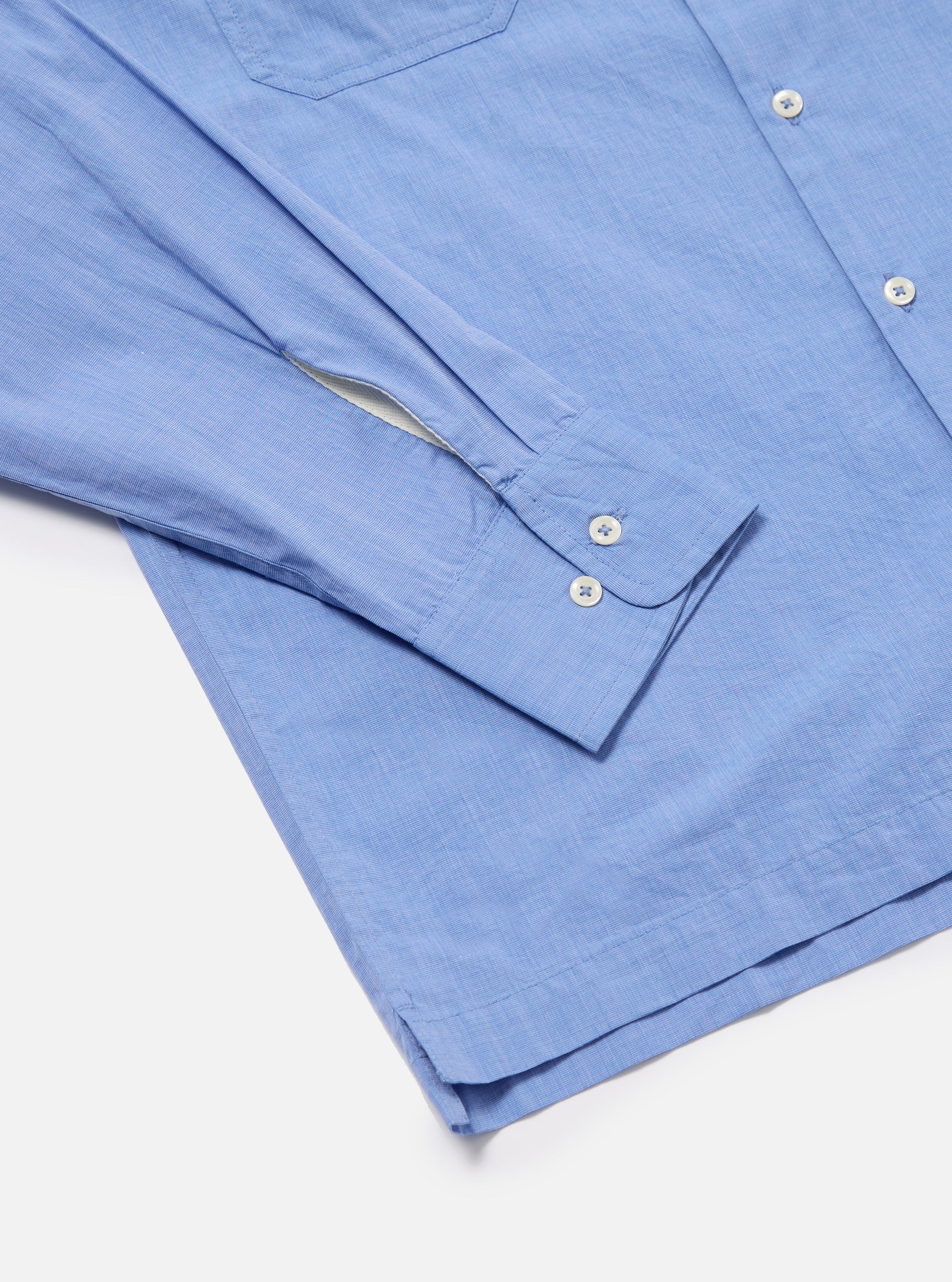 Close-up of the Blue End On End Cotton Garage Shirt on a white background. Shows the light blue cotton fabric, button details, and sleeve cuff.