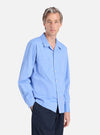 A man models the Blue End On End Cotton Garage Shirt. The light blue shirt is cotton and worn with dark pants against a white background.