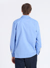 Back view of a man wearing a Blue End On End Cotton Garage Shirt. The light blue shirt is paired with dark pants, against a white backdrop.