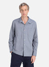 A man models the Grey End On End Cotton Garage Shirt. The light blue shirt is cotton and worn with dark pants, against a white backdrop.