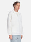 A man models the Ecru Deffe Self Stripe Smock Overshirt in a studio setting. The shirt is ecru with subtle stripes and a relaxed fit.