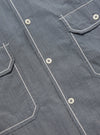 Close-up of the Grey End On End Cotton Utility SS Shirt. Shows the texture of the grey cotton, white buttons, and contrasting white stitching on the pockets and placket.