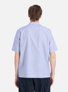 Back view of a man wearing a Blue Classic Stripes Road Trip Shirt. The shirt is light blue with subtle stripes. The background is a plain white studio setting.