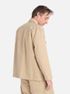 A man models the Sand Military Cotton Dockside Overshirt in a studio setting. The overshirt is a light sand color and appears to be made of cotton. The background is a clean white.