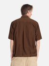 Back view of a man wearing the Khaki Summer Cord Tech Overshirt in brown corduroy with khaki pants, against a white background. The overshirt has short sleeves and a relaxed fit.