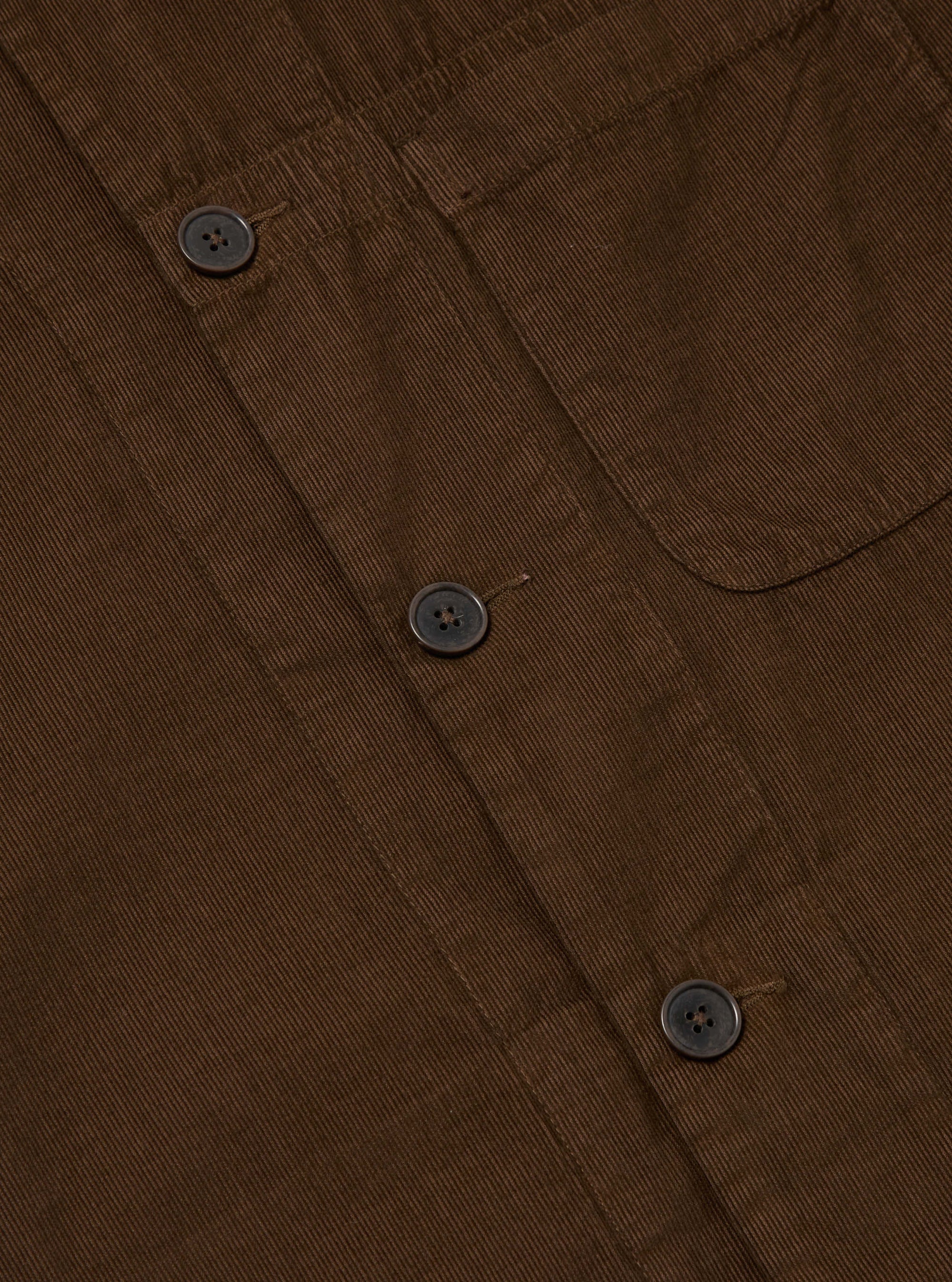 Close-up of the Khaki Summer Cord Tech Overshirt, showcasing its brown corduroy texture, button details, and pocket. Shot on a flat, neutral surface.