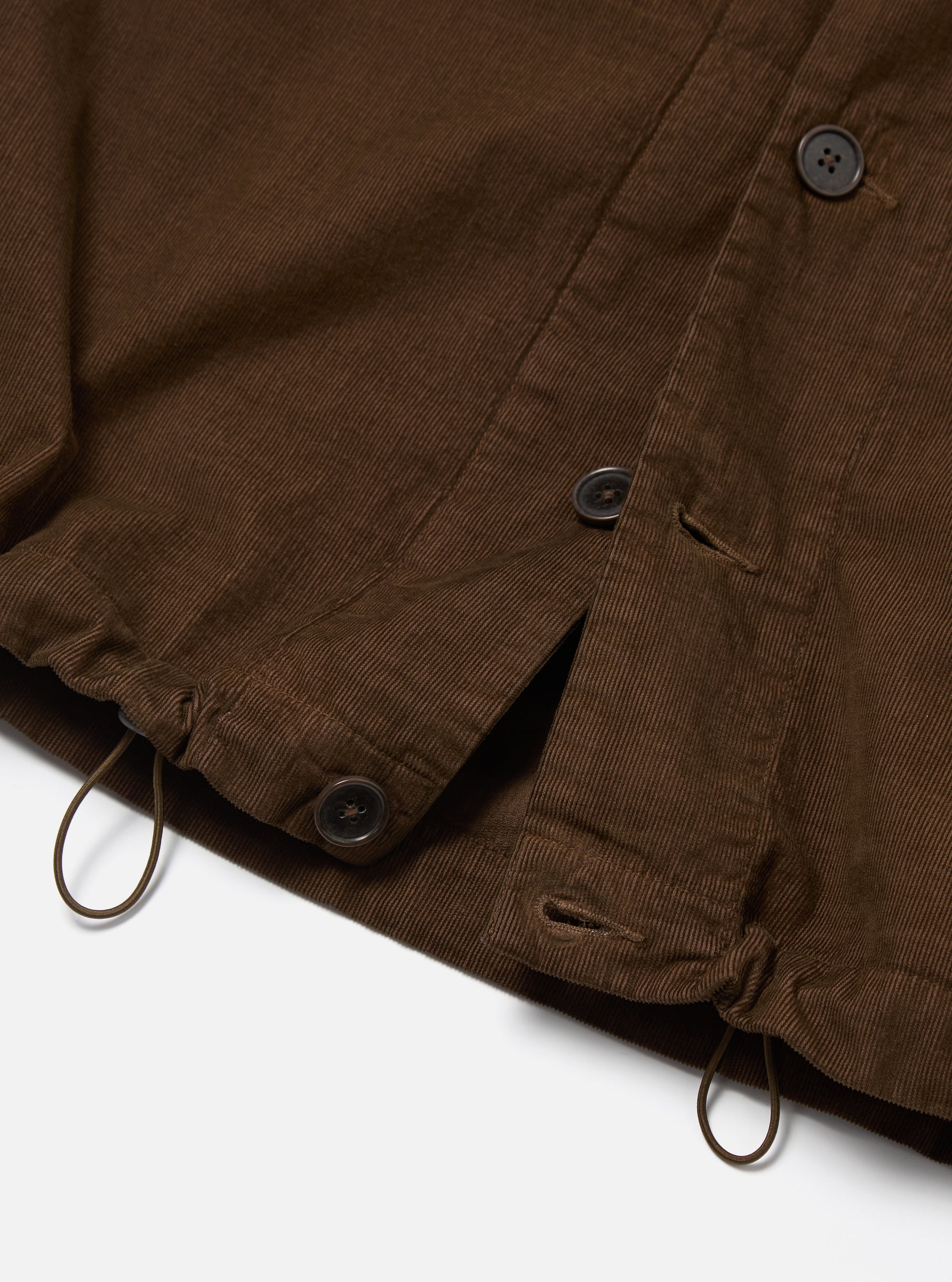 Close-up of the Khaki Summer Cord Tech Overshirt in brown corduroy. Features include button closure, drawstring, and a clean white background.