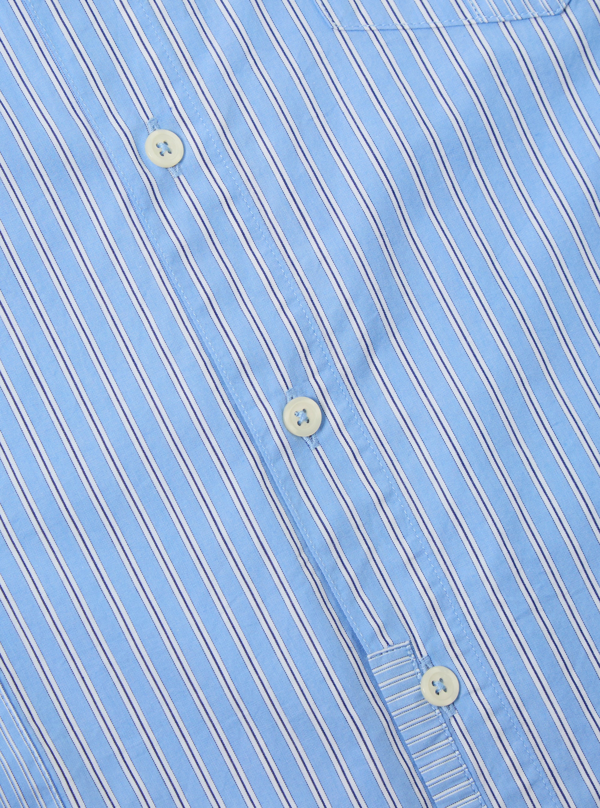Close-up of the Blue Vila Stripes Patched Shirt. Features light blue and white stripes with navy accents, button-down style. Shot on a flat surface.